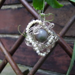 an agate bead surrounded by silver wire and pearls